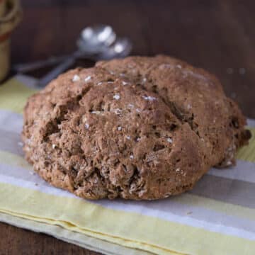 A photo of Irish brown bread on a kitchen towel and soup bowls in the background.