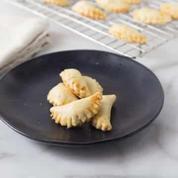 A photo of mini crab meat empanadas in black plate.